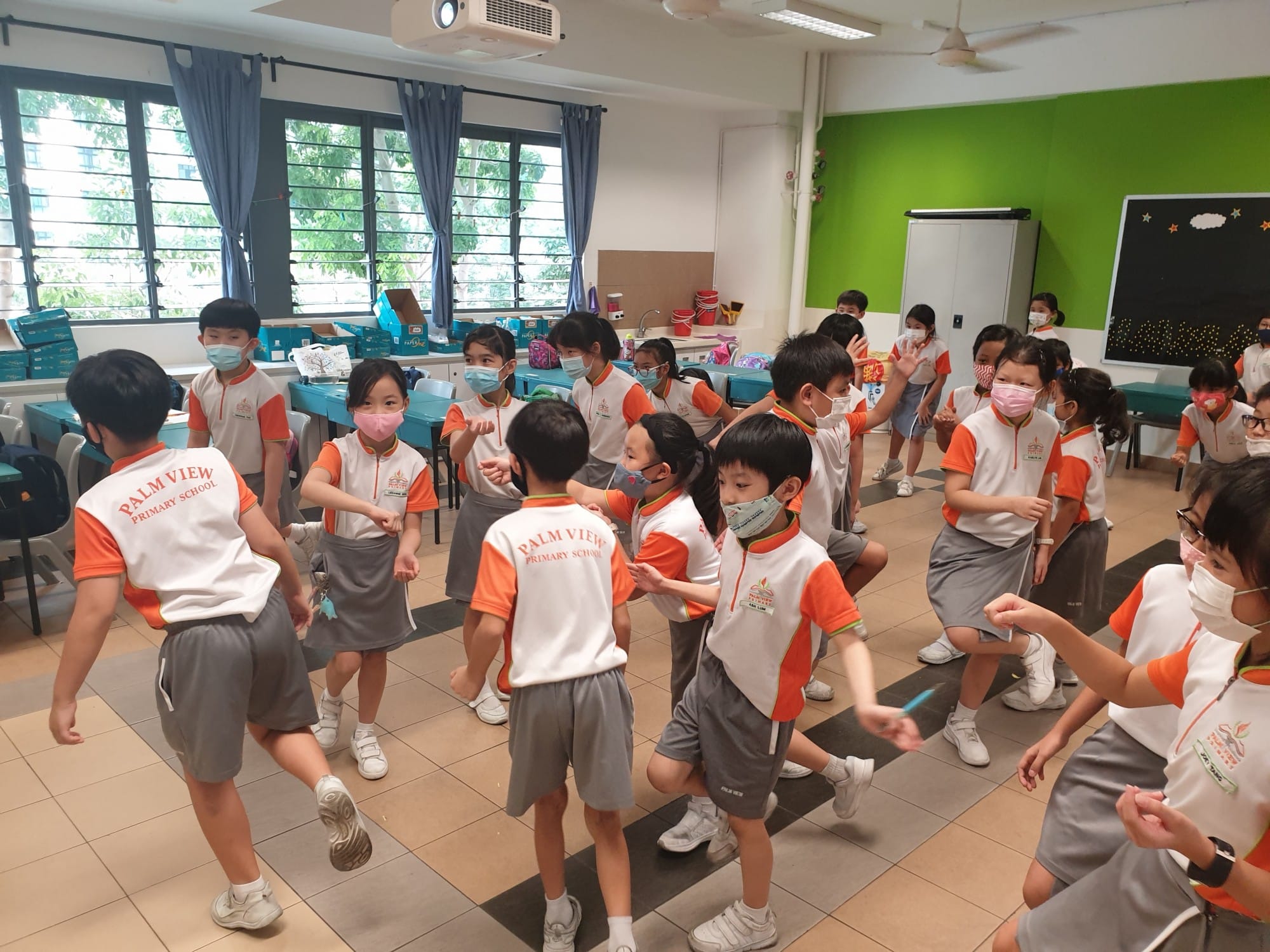 Young students in Palm View Primary School uniforms and face masks do an activity together in a bright classroom.